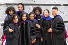 A group of smiling African American graduates standing in front of Wood Fountain at IUPUI.